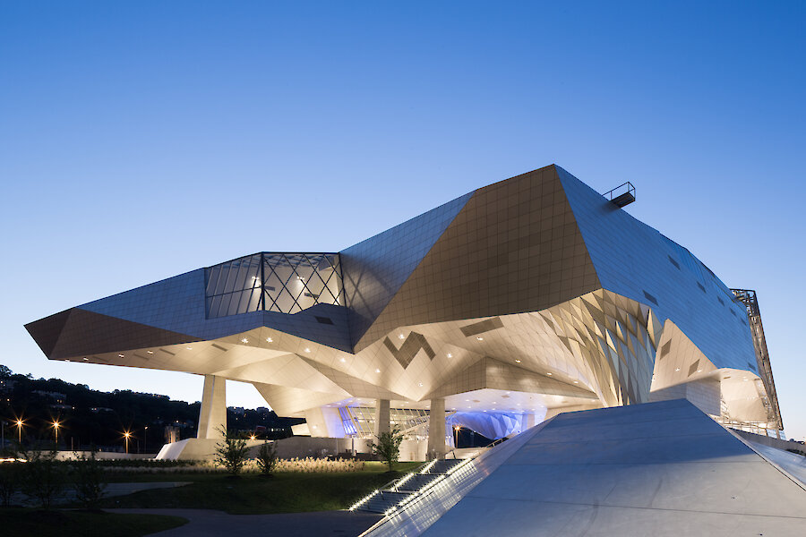 Se muestra al edificio desde otro punto de vista , en este caso de noche, se puede apreciar la iluminación y como esta va conjugando la forma del Museo Musée des Confluences